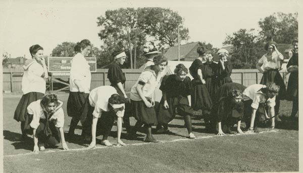 black and white photograph of several women at the start of a race, wearing both light and dark uniforms
