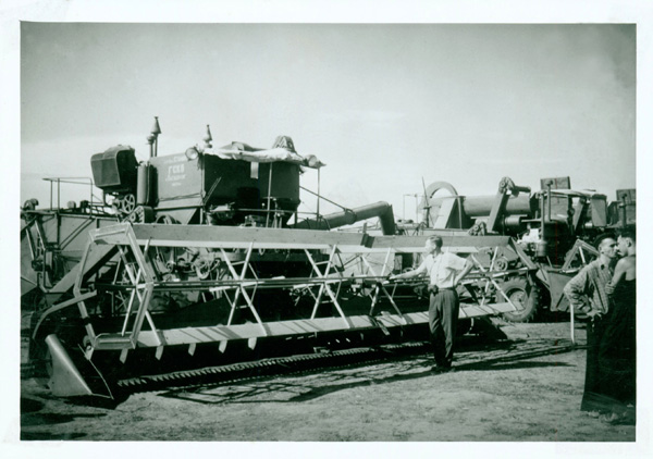 Photograph of a man standing next to a Russian combine, possibly from a professor's trip to Europe and Russia.