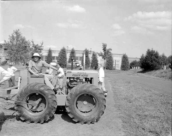 Picture of a Harris four wheel drive tractor being admired as a part of the Tractor Day on East Campus.