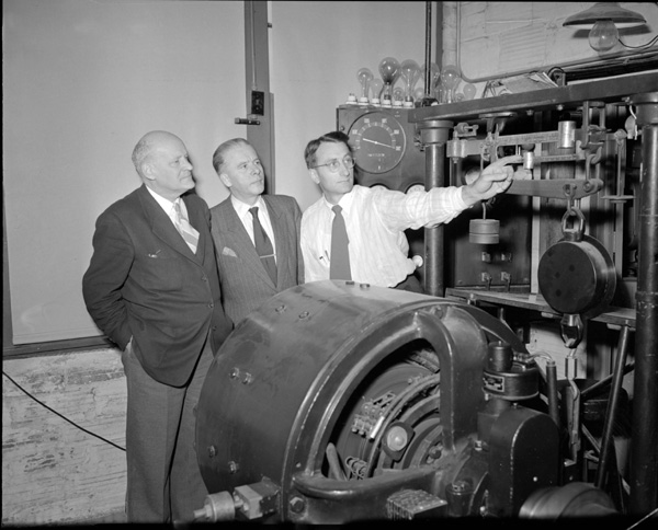 A picture of Lester Larsen showing Joochin Pohl and August Hassler from Germany
               the Tractor Test Lab's dynamometer.